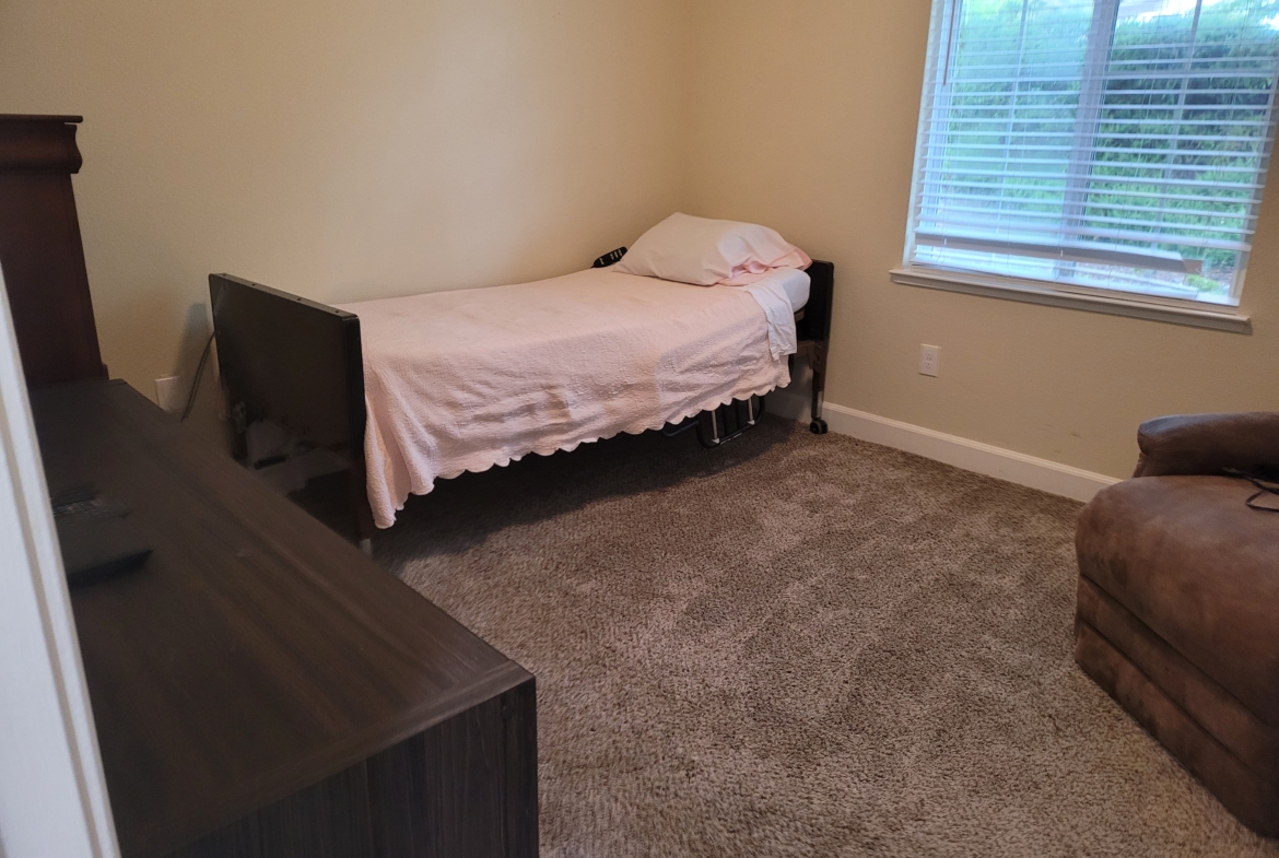 A bed room with a single bed and a desk