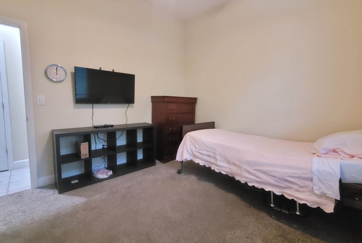 A bed room with a tv and a small cabinet