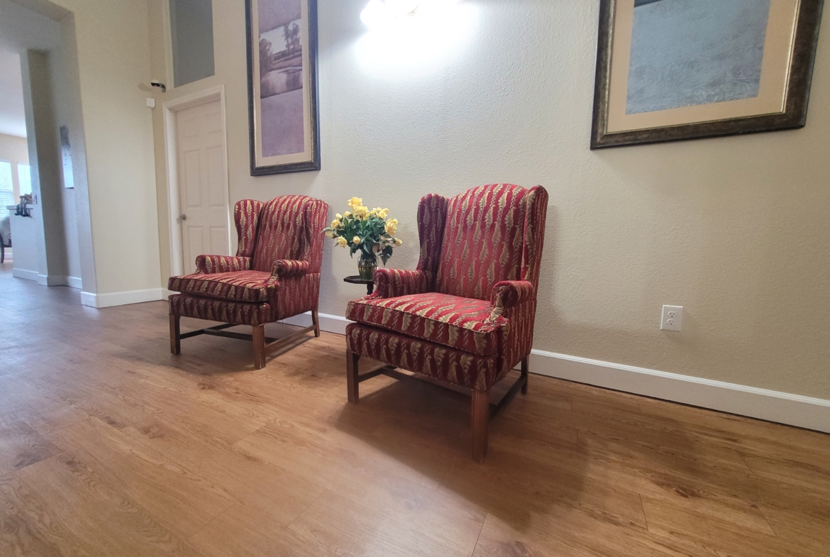 Two chairs in a room with a vase of flowers.