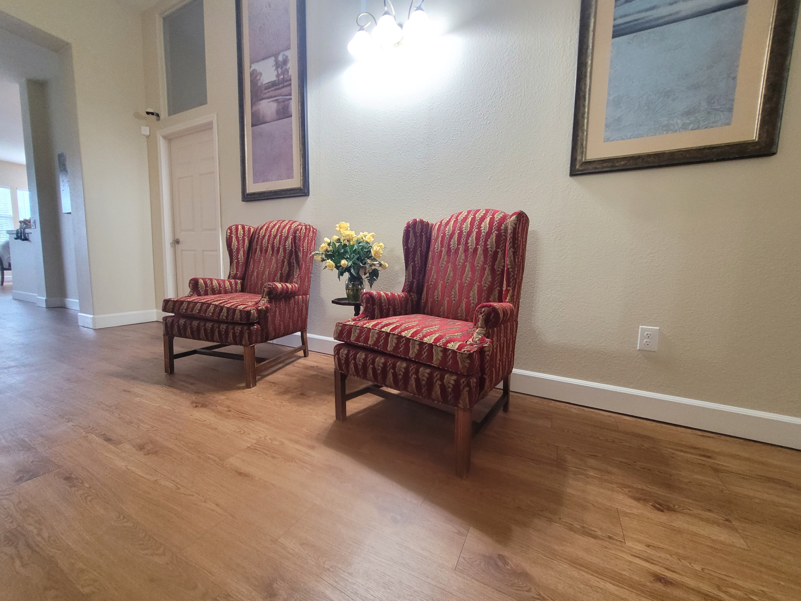 Two chairs in a room with a vase of flowers.