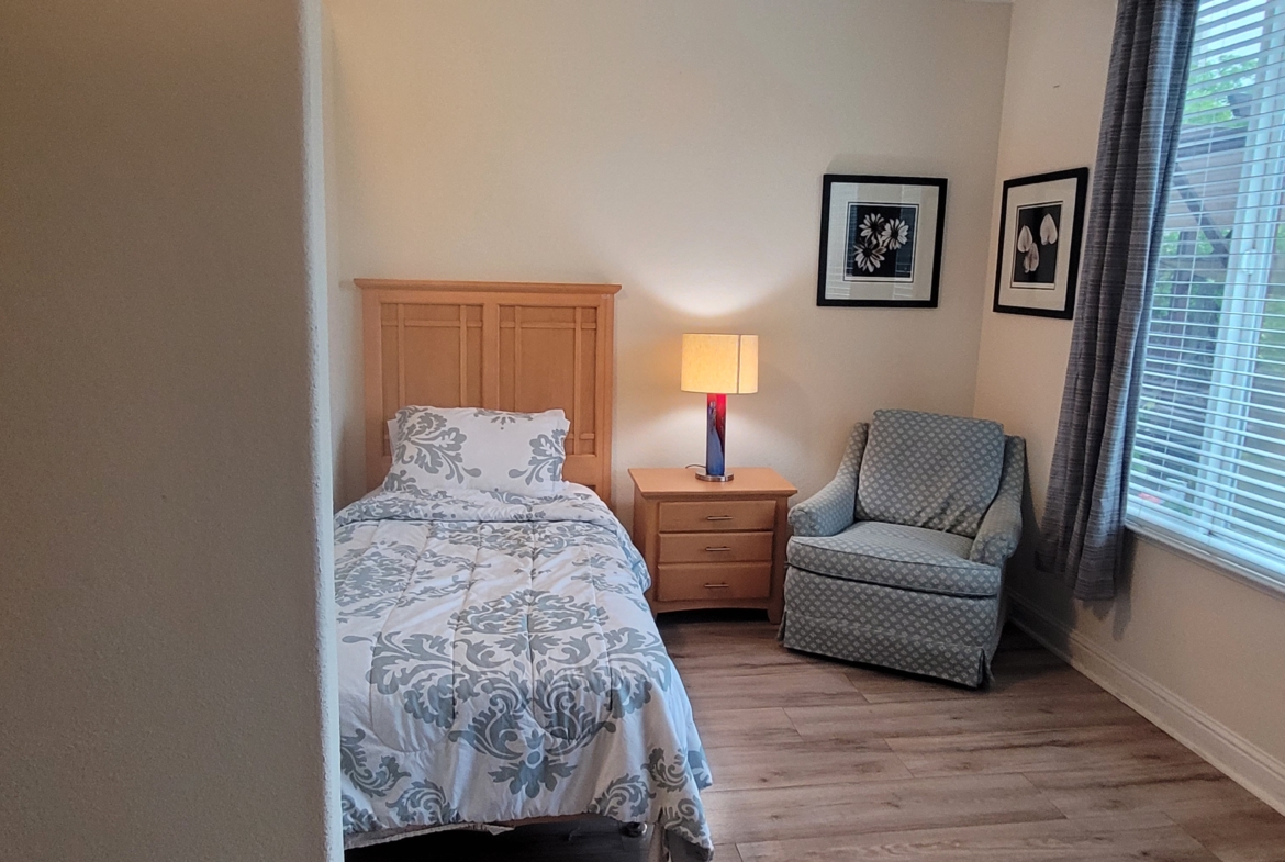 A bedroom with a bed, chair and window.