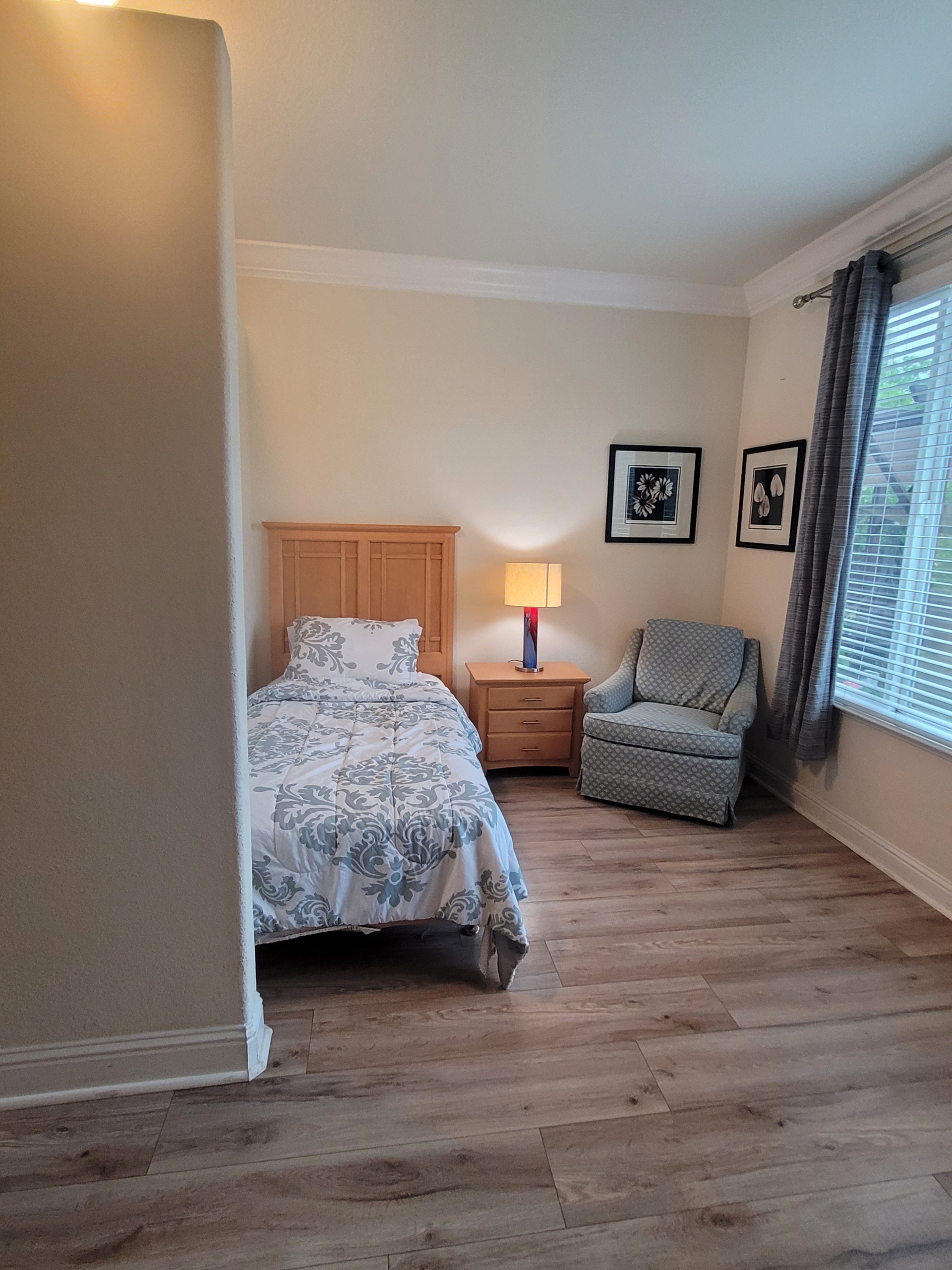 A bedroom with a bed, chair and window.