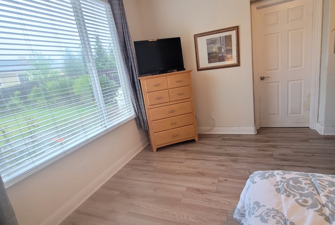 A bedroom with hard wood floors and a television.