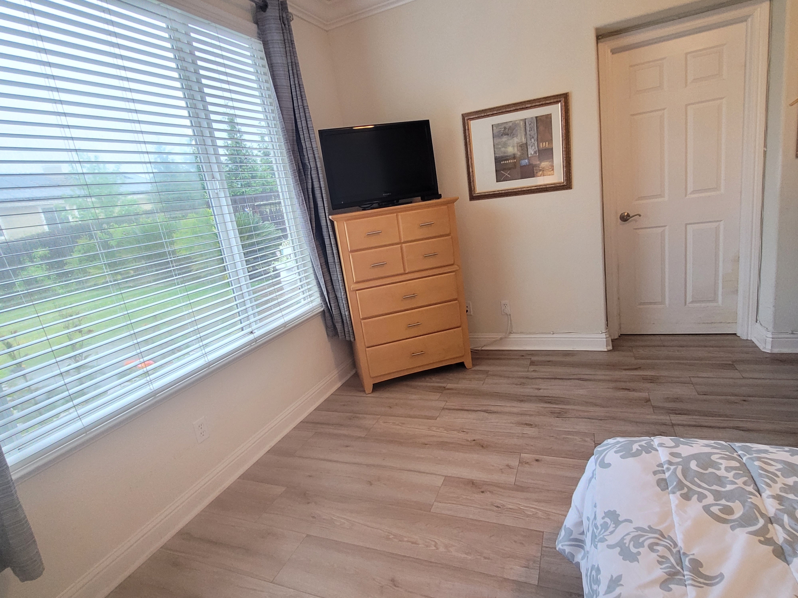 A bedroom with hard wood floors and a television.