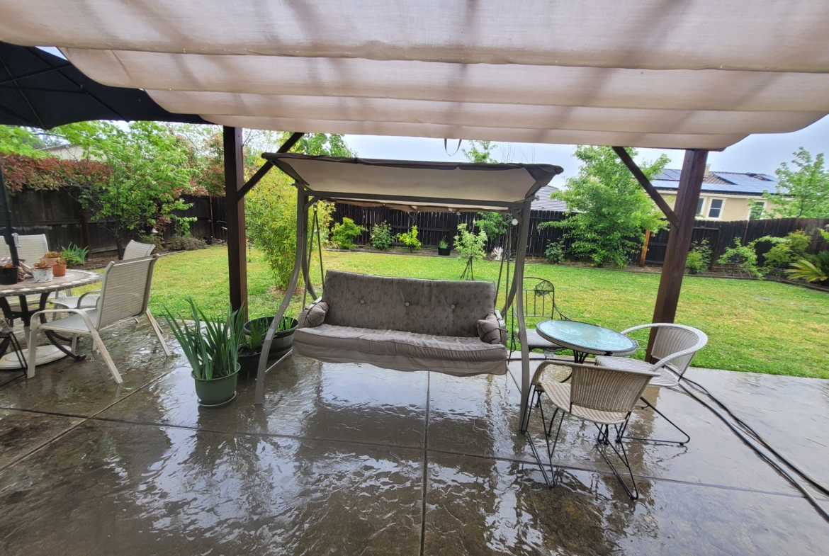 A patio with a swing and table in it