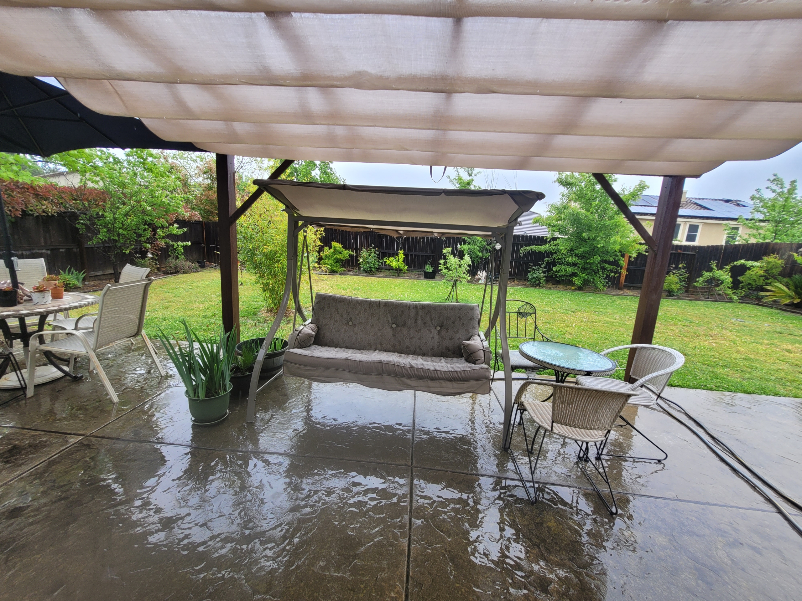 A patio with a swing and table in it