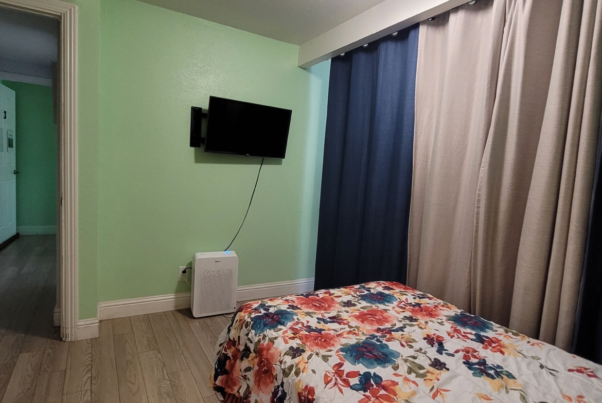 A bedroom with a bed and television in it.