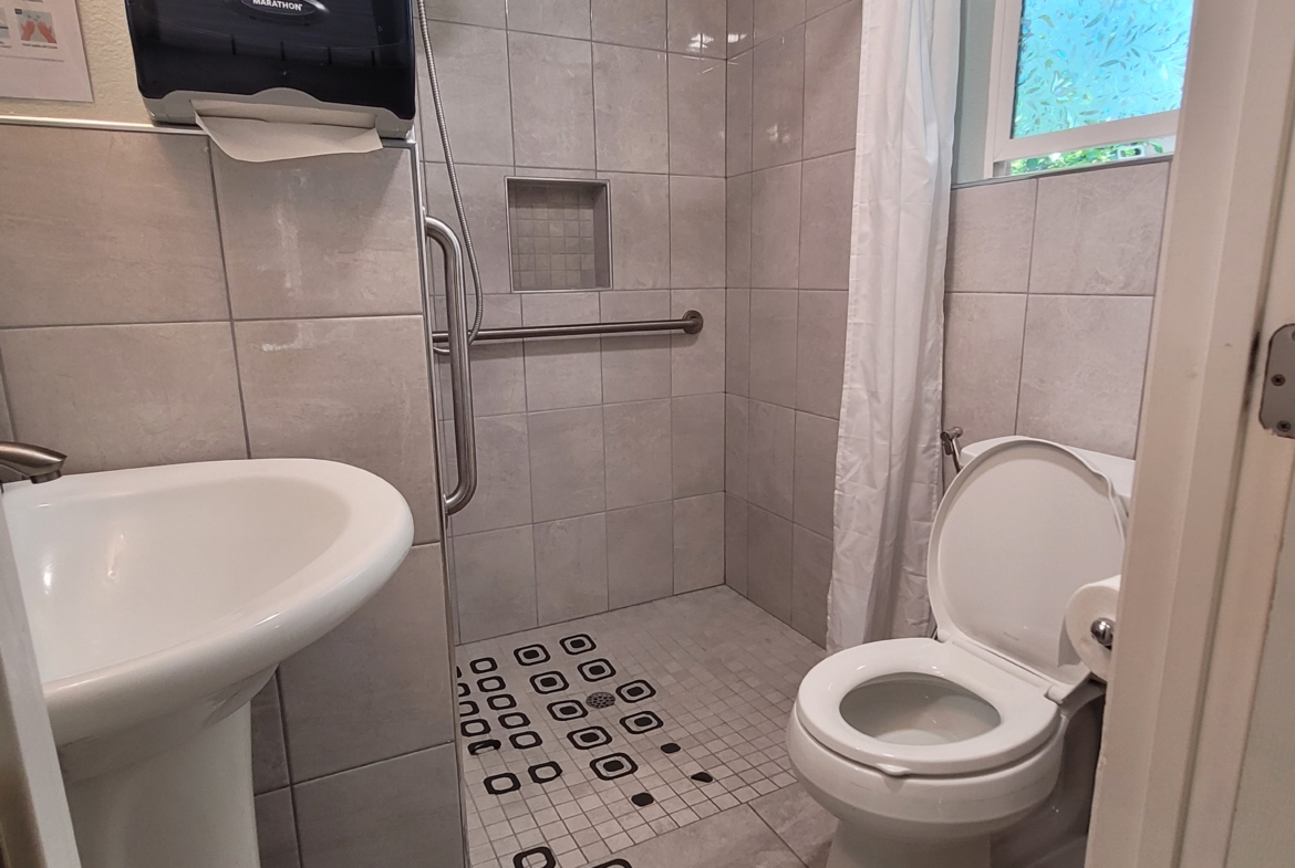 A bathroom with a toilet, sink and shower.