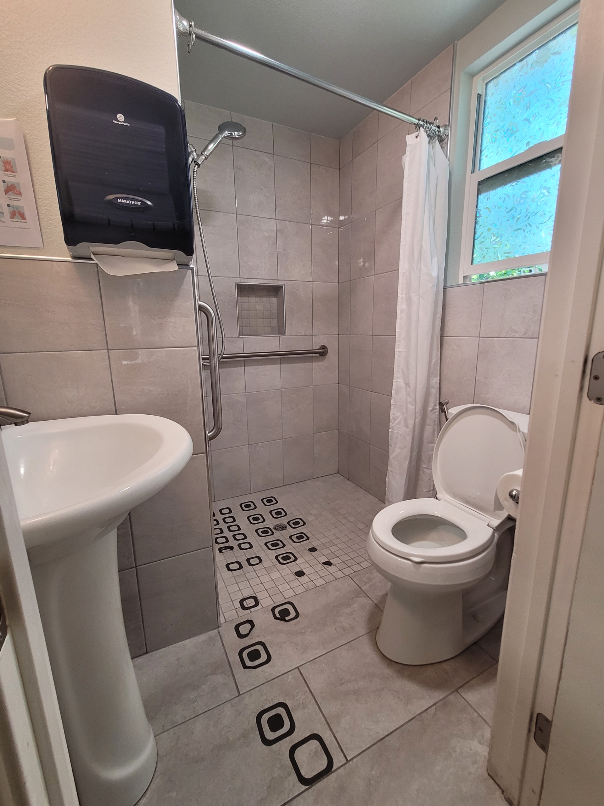 A bathroom with a toilet, sink and shower.