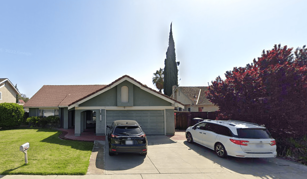 A house with two cars parked in front of it.