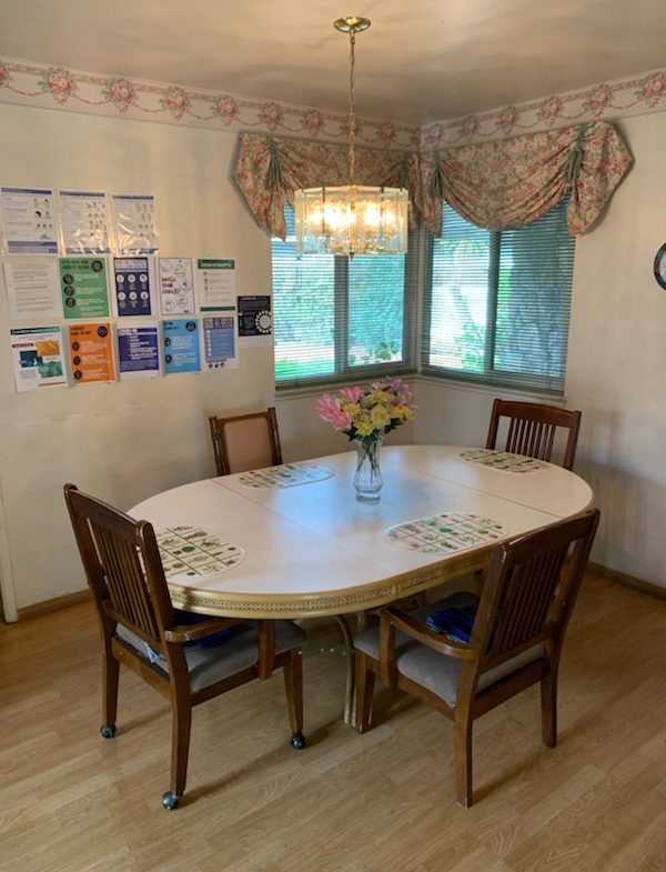 A dining room table with four chairs and a vase of flowers.