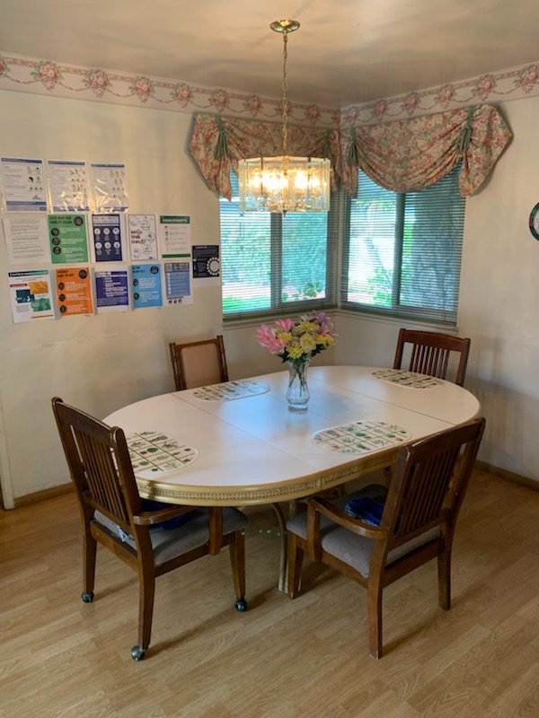 A dining room table with four chairs and a vase of flowers.