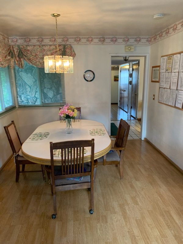 A dining room table with chairs and a vase of flowers.