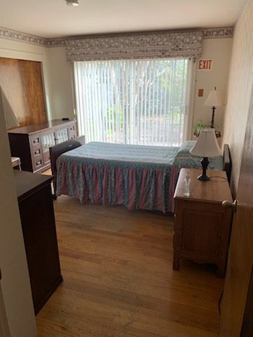 A bedroom with a bed, dresser and window.