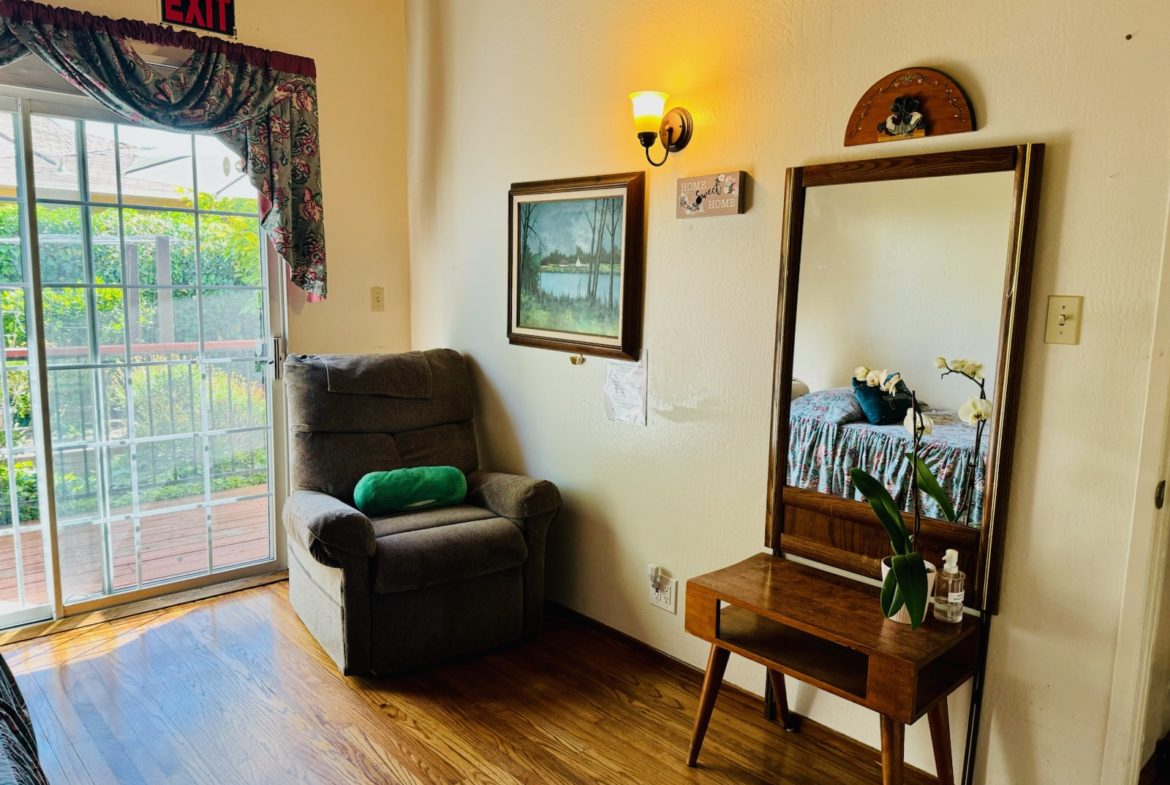 A living room with a chair, mirror and table.