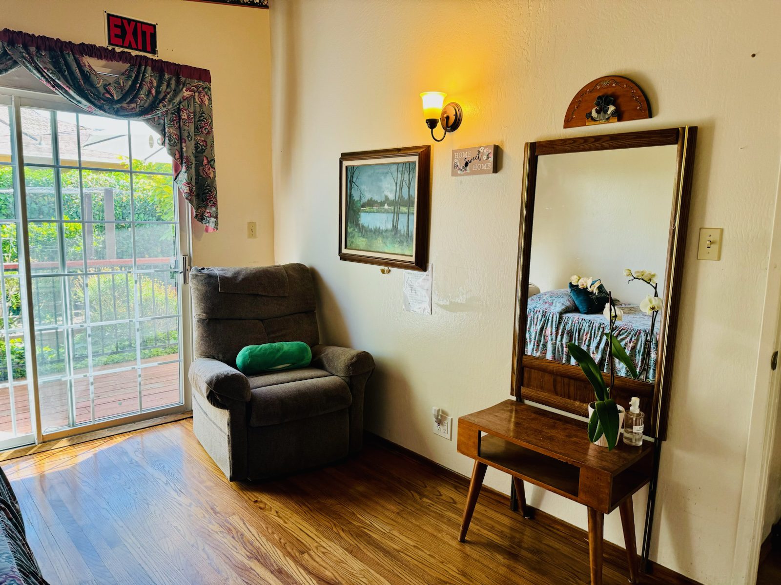 A living room with a chair, mirror and table.