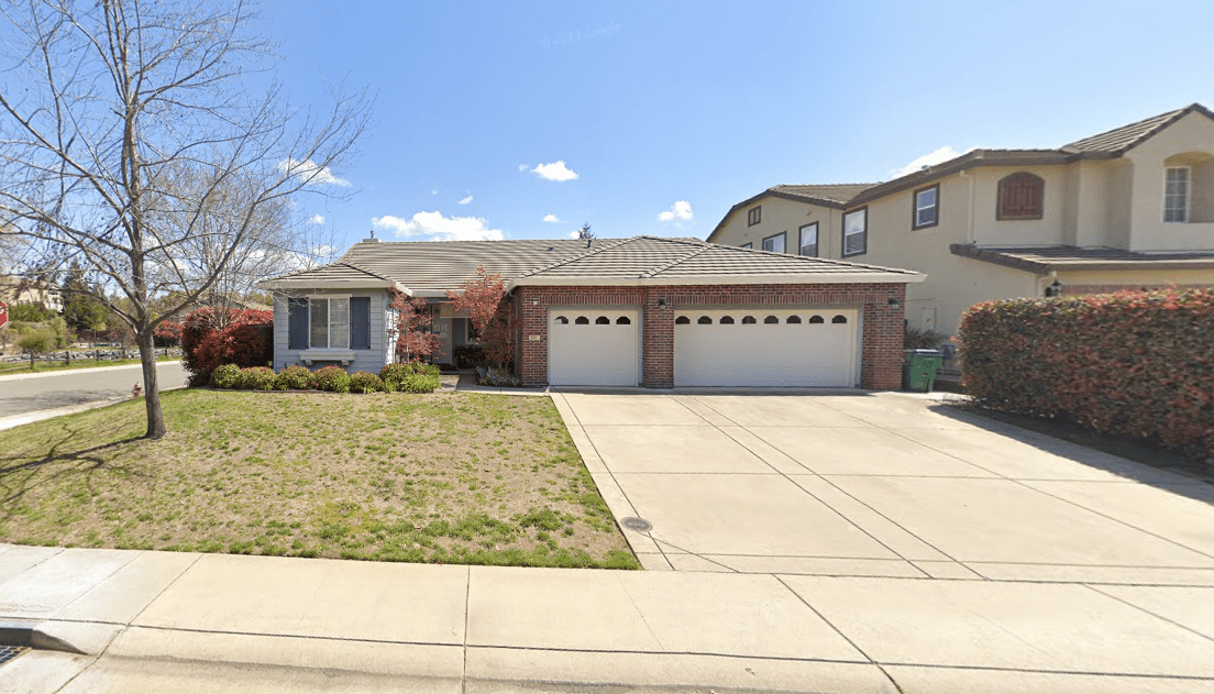 A large house with two garage doors and a driveway.