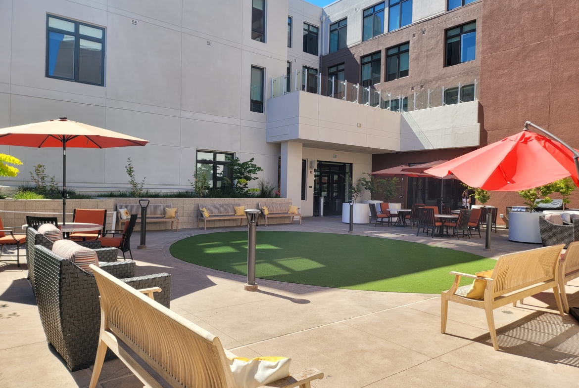 A courtyard with lawn chairs and umbrellas.