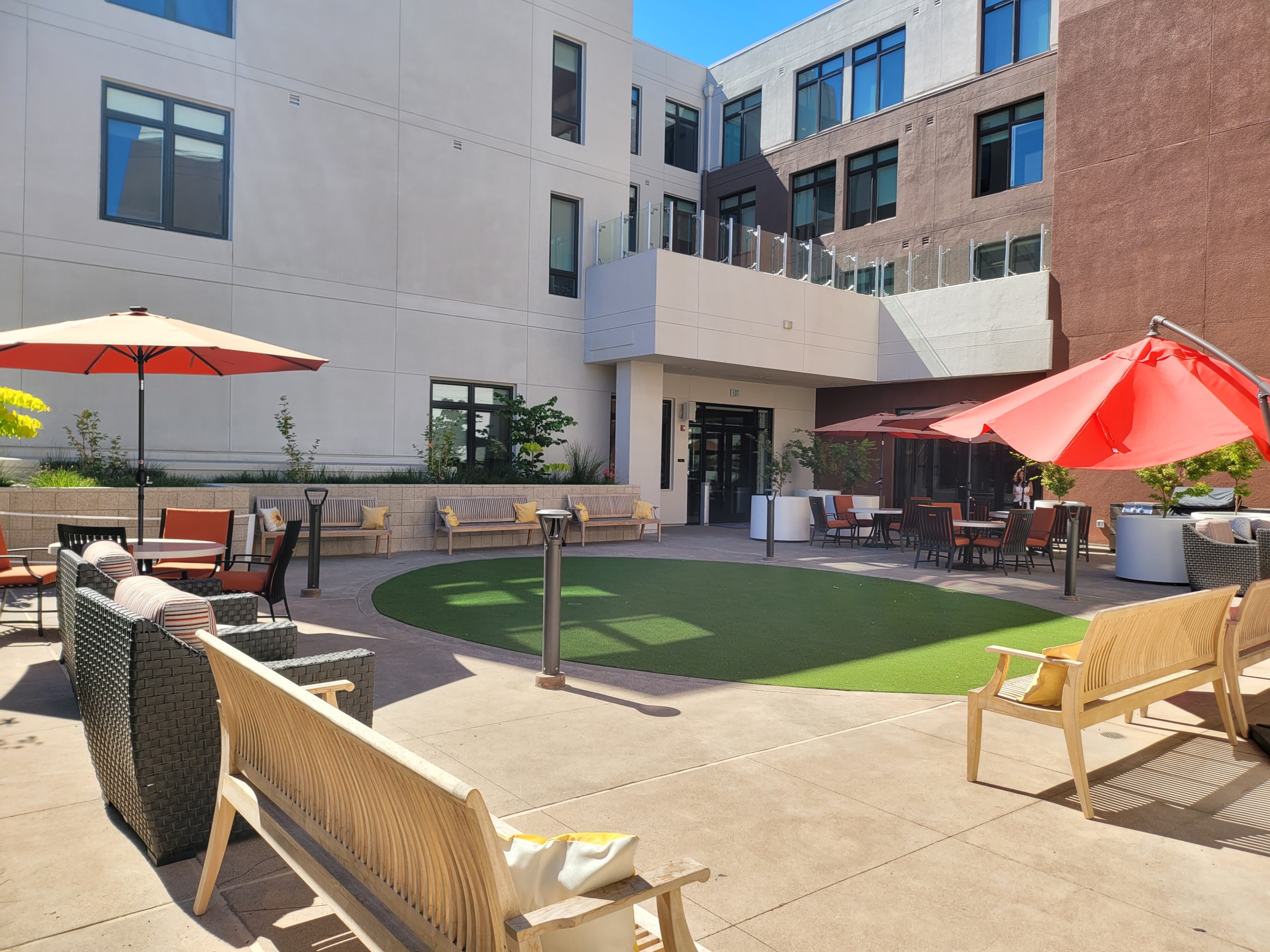 A courtyard with lawn chairs and umbrellas.