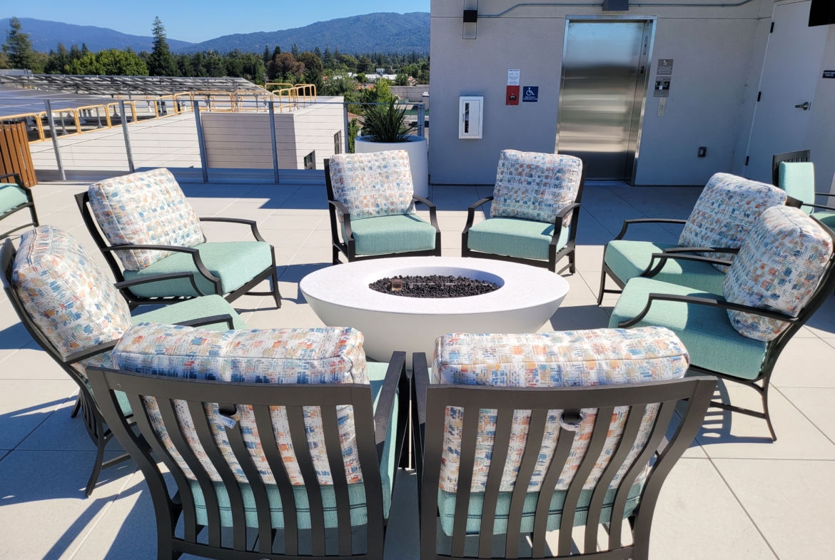 A group of chairs and tables around an outdoor fire pit.