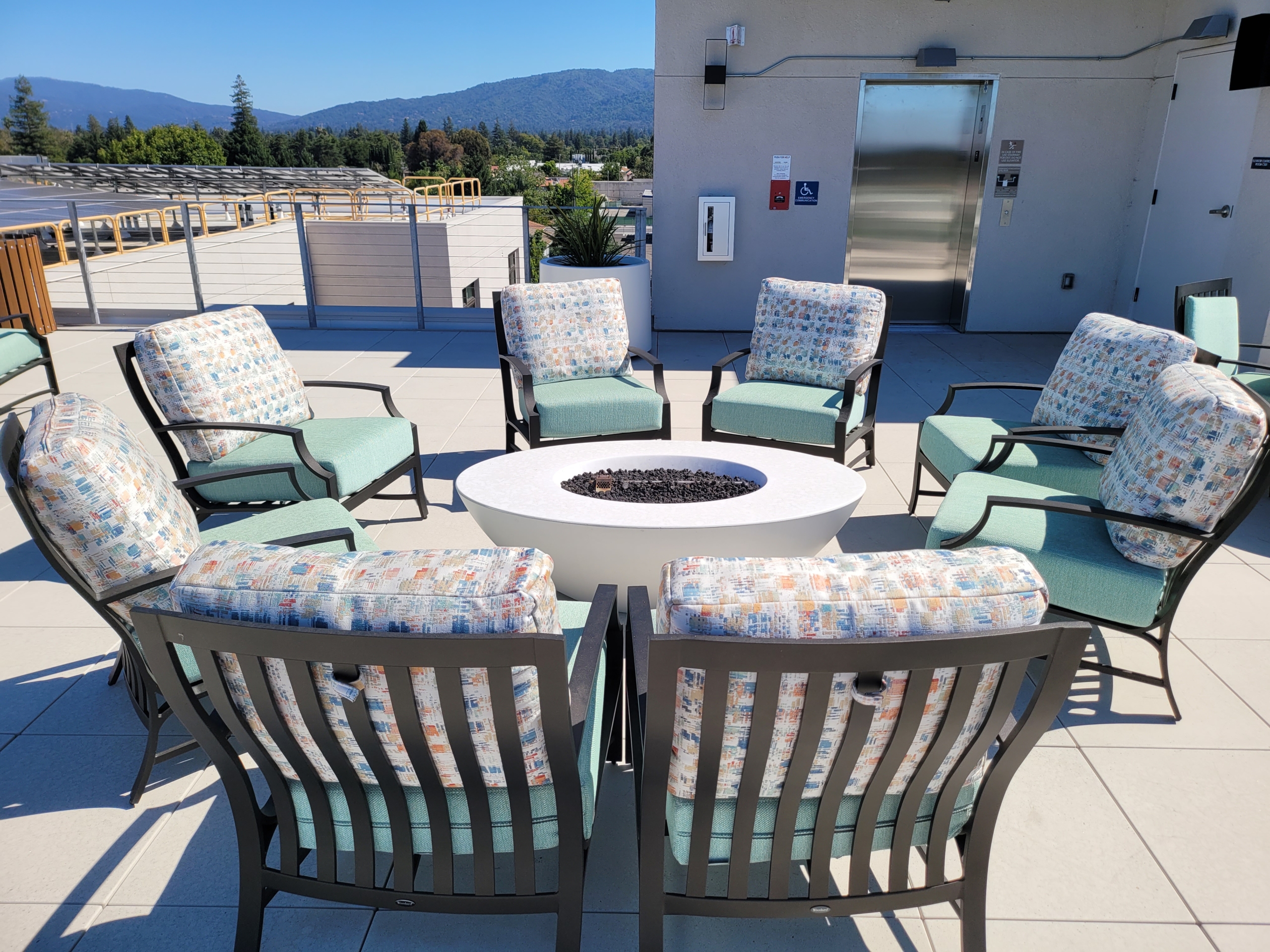 A group of chairs and tables around an outdoor fire pit.