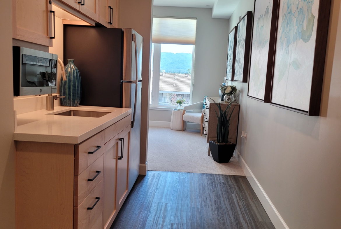 A kitchen with a refrigerator, sink and microwave.