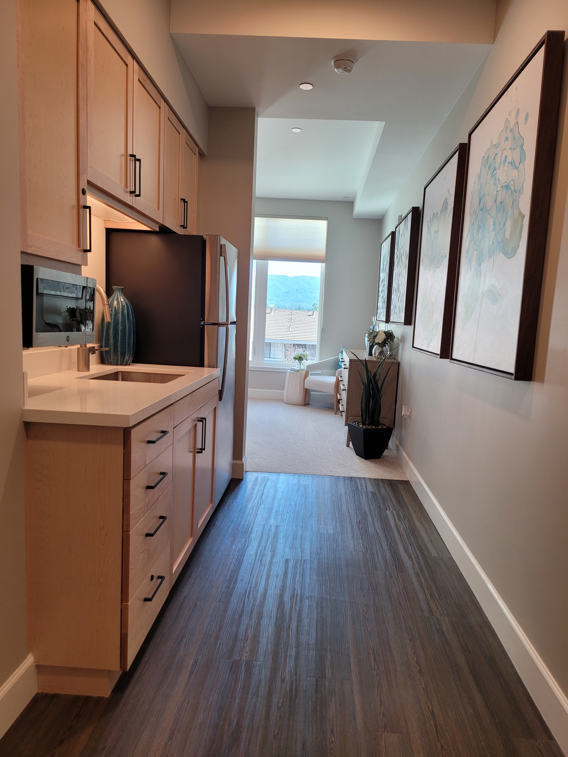 A kitchen with a refrigerator, sink and microwave.