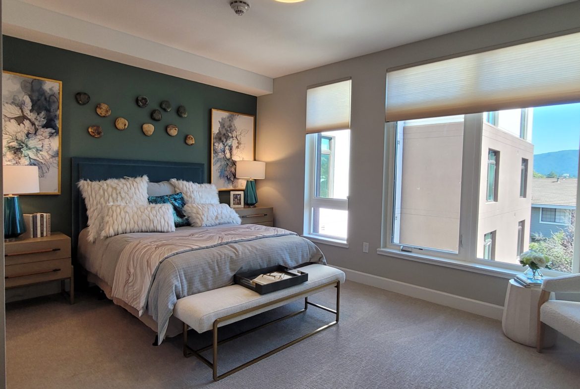 A bedroom with a bed, window and bench.