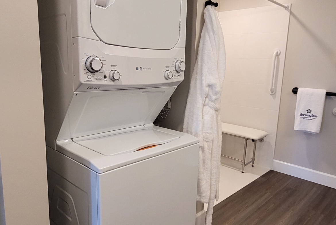 A white washer and dryer in the corner of a room.