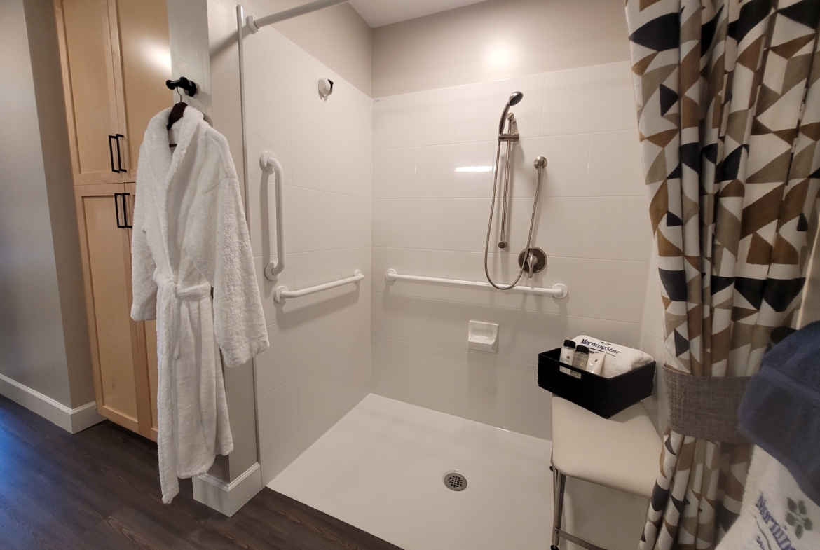 A bathroom with a walk in shower and white tile walls.