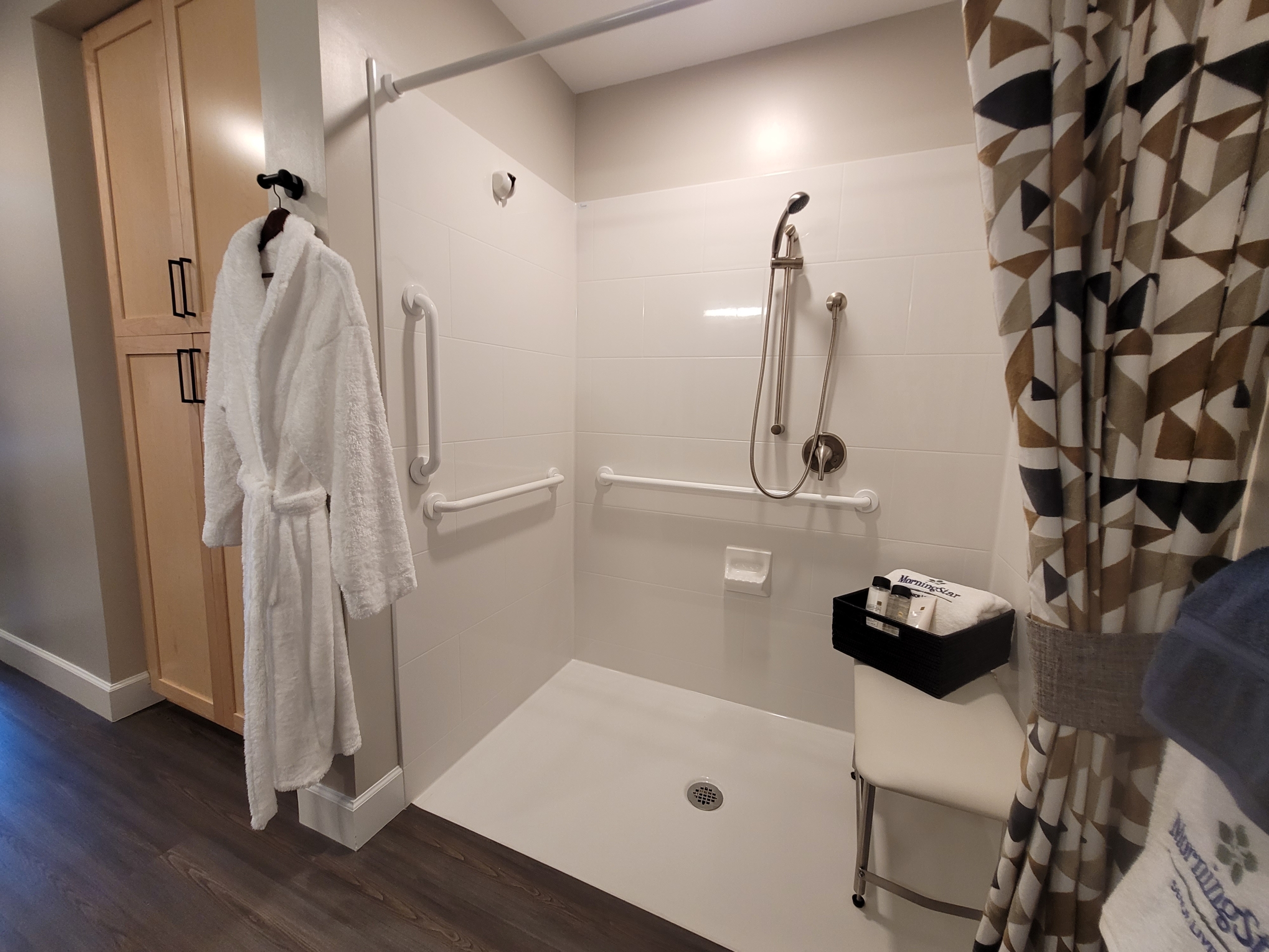 A bathroom with a walk in shower and white tile walls.