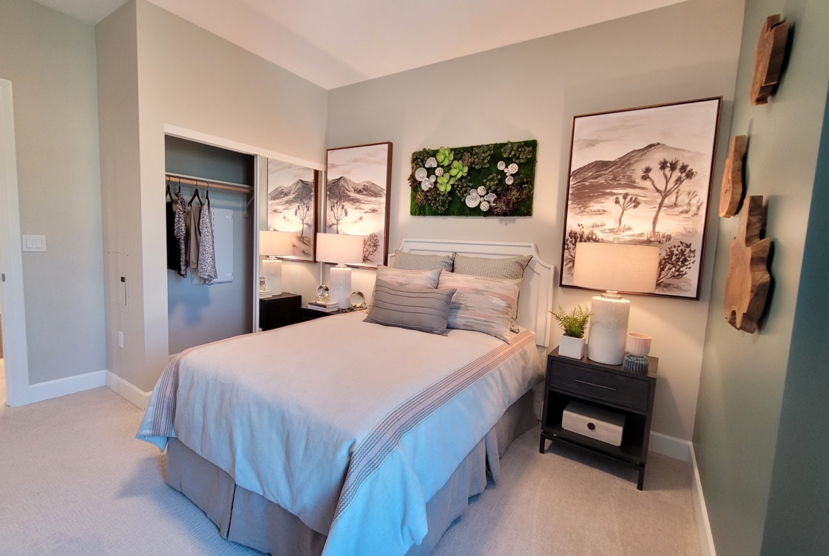 A bedroom with two large paintings above the bed.