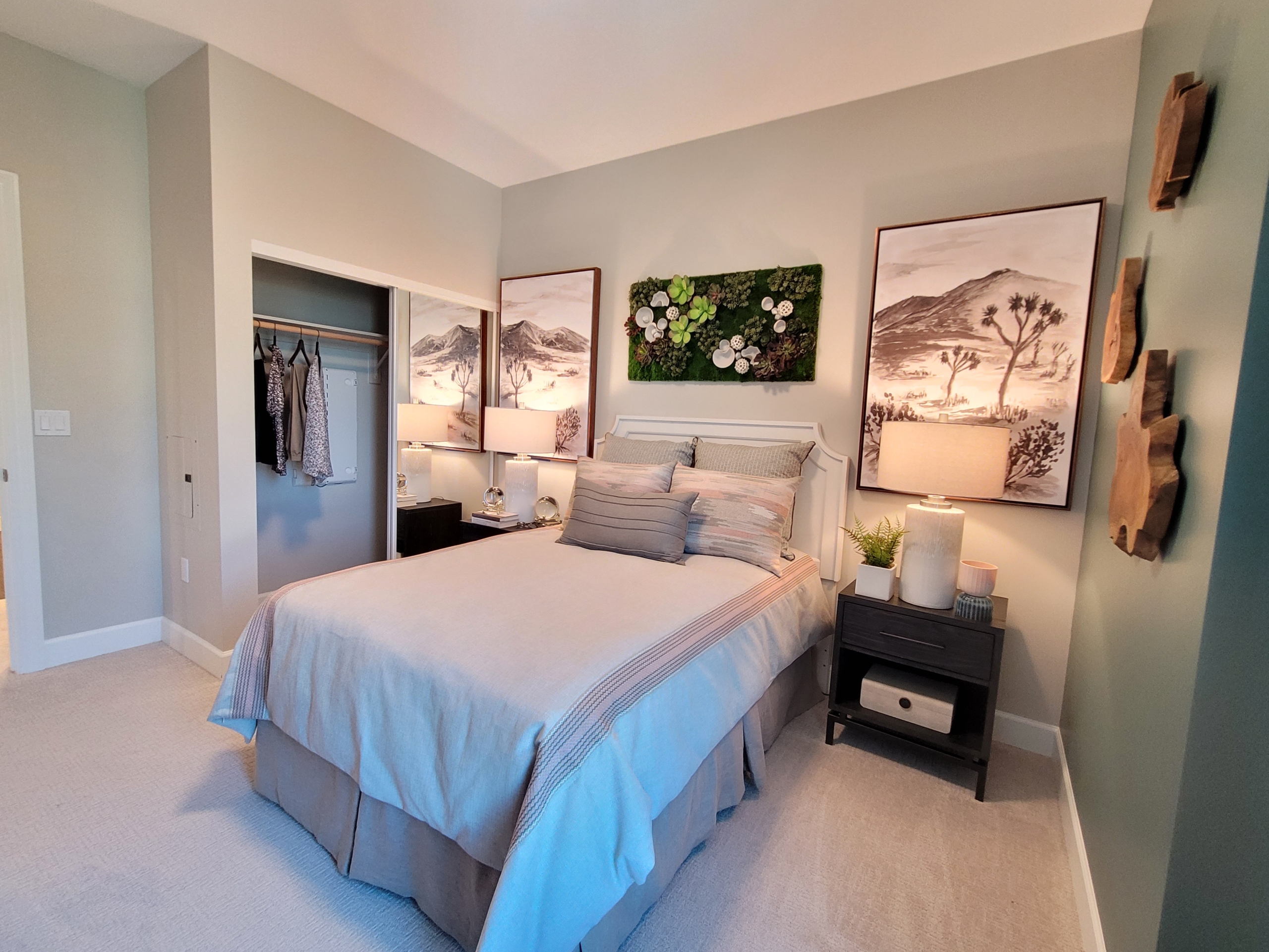 A bedroom with two large paintings above the bed.