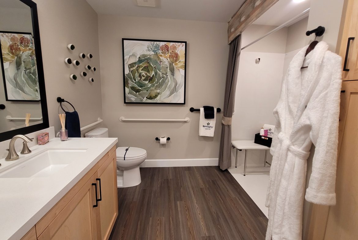 A bathroom with wood floors and white fixtures.