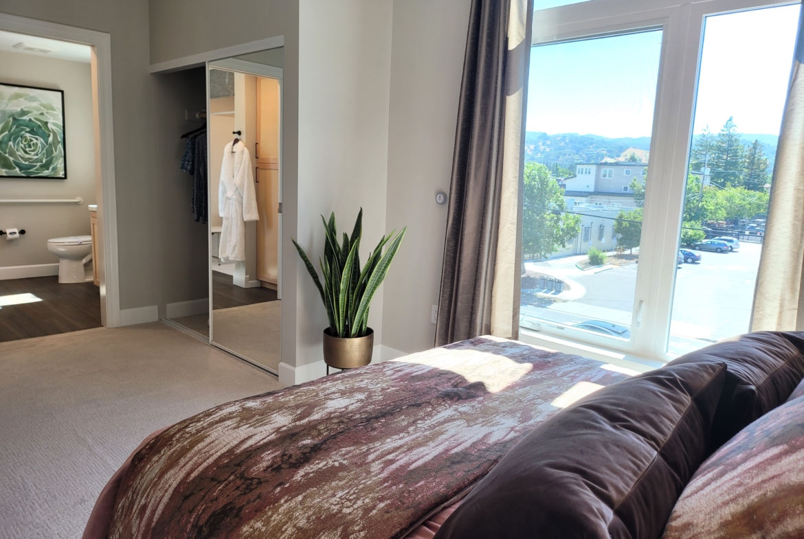 A bedroom with a large window and a view of the mountains.