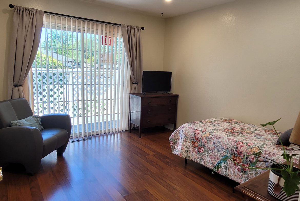 A bedroom with a bed, chair and television.