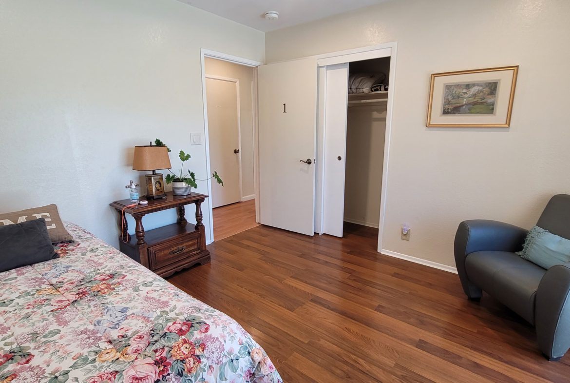 A bedroom with hard wood floors and a bed.