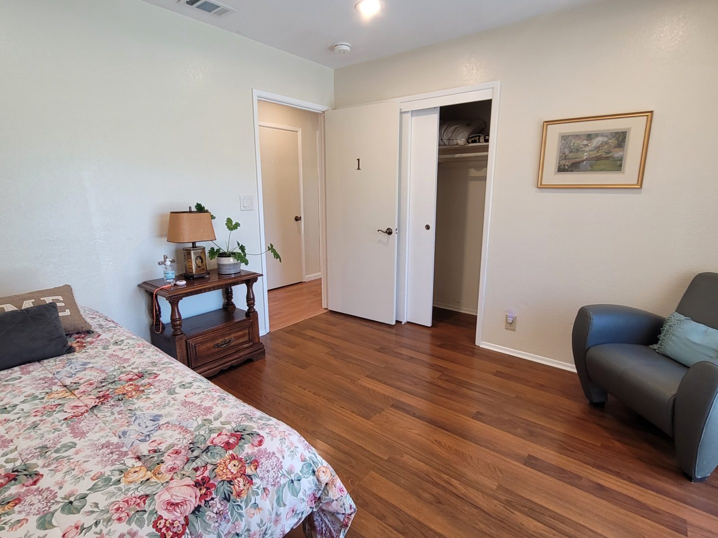 A bedroom with hard wood floors and a bed.