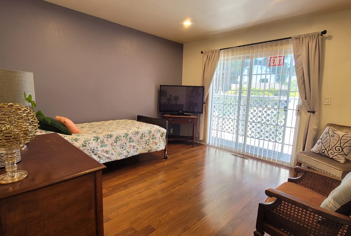 A bedroom with a bed, television and balcony.