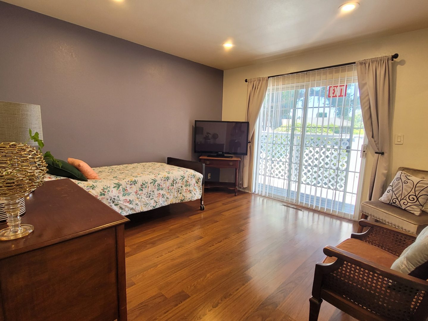 A bedroom with a bed, television and balcony.