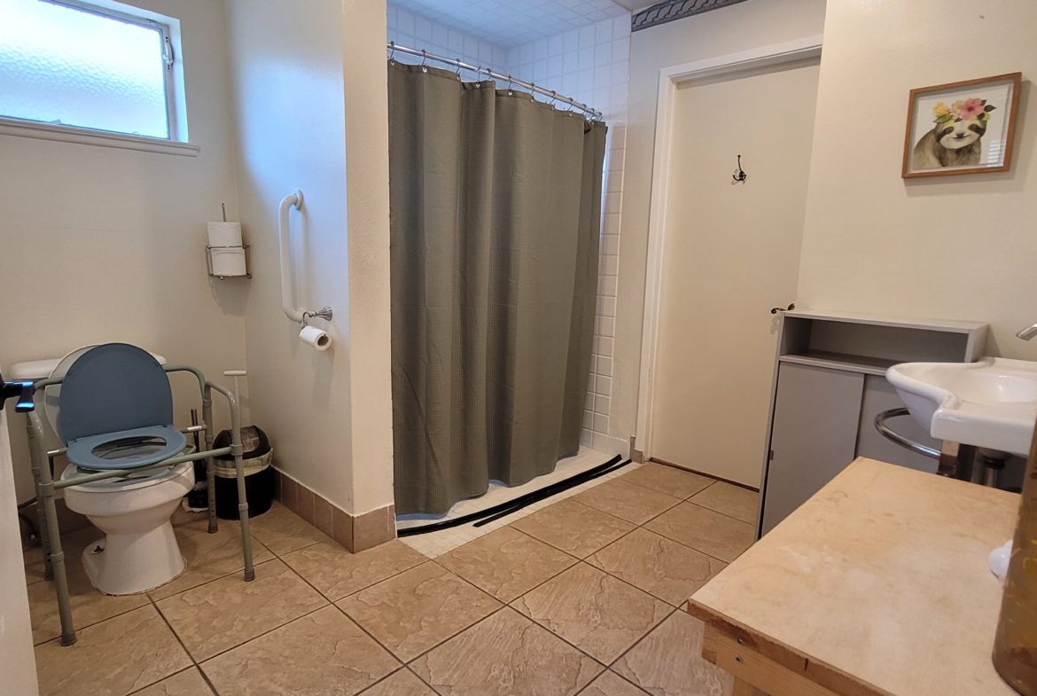 A bathroom with a toilet, sink and shower.