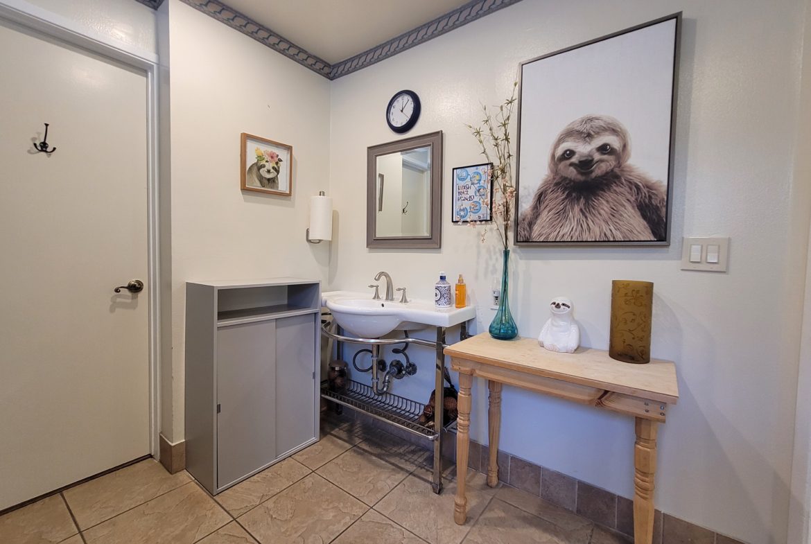 A bathroom with a sink, mirror and table.