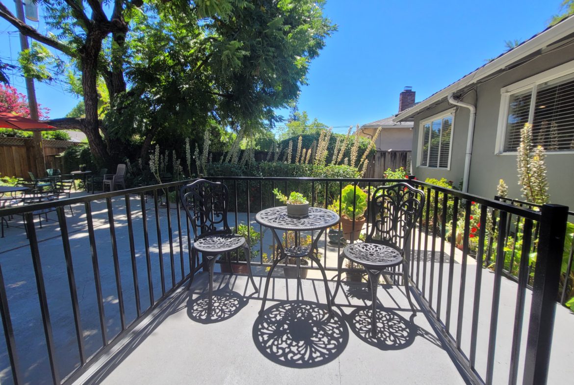 A patio with two tables and chairs on the back deck.