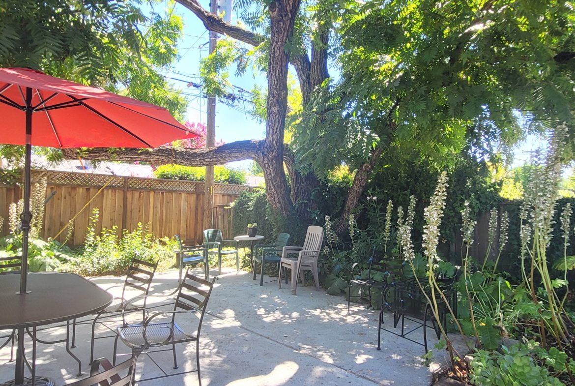 A patio with chairs and an umbrella in the background.