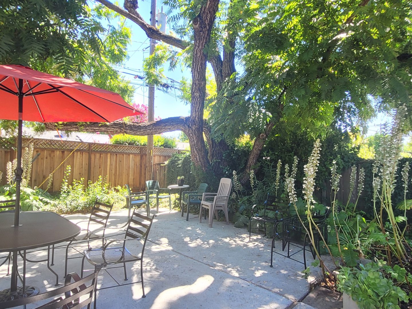 A patio with chairs and an umbrella in the background.