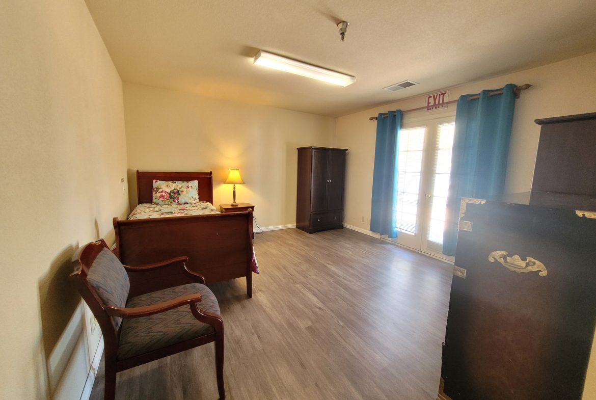 A bedroom with hard wood floors and furniture.