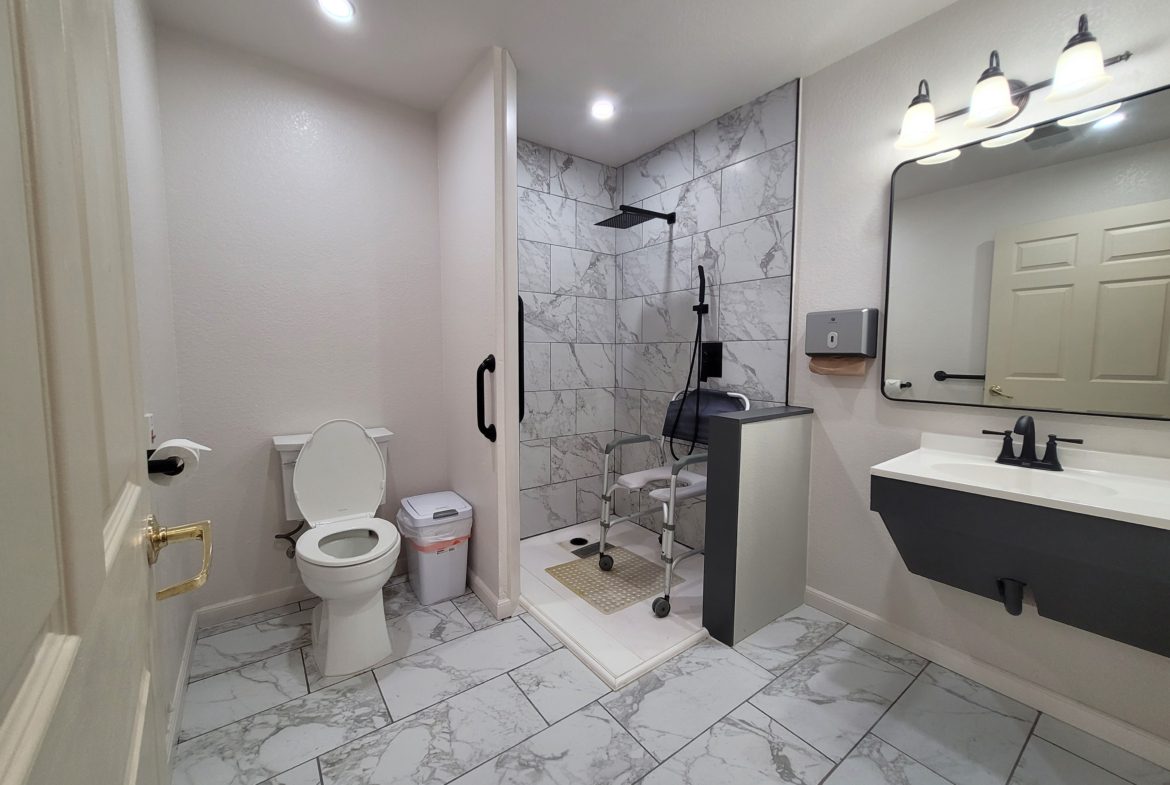 A bathroom with a toilet, sink and mirror.