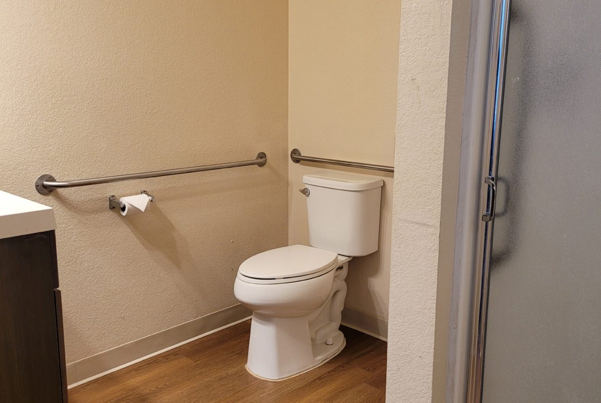 A bathroom with wood floors and white walls.