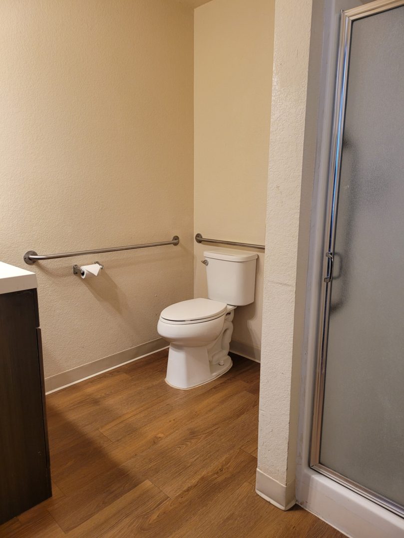 A bathroom with wood floors and white walls.