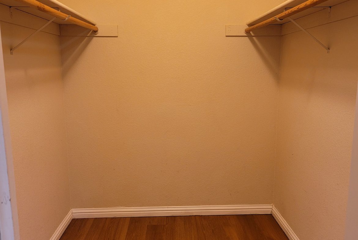 A closet with two wooden shelves and one is open.